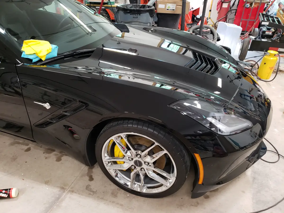 Close-up of a chrome Corvette wheel with yellow brake calipers after detailing