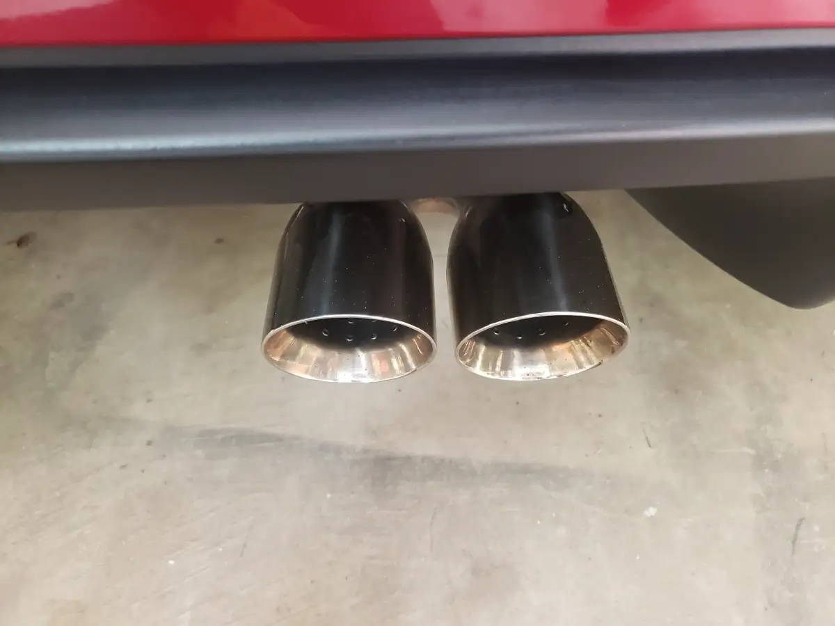 Close-up of polished dual chrome exhaust tips on a red vehicle
