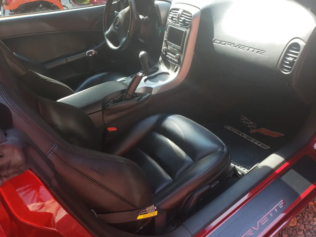 Clean black leather Corvette interior showing driver seat, console, and door sill