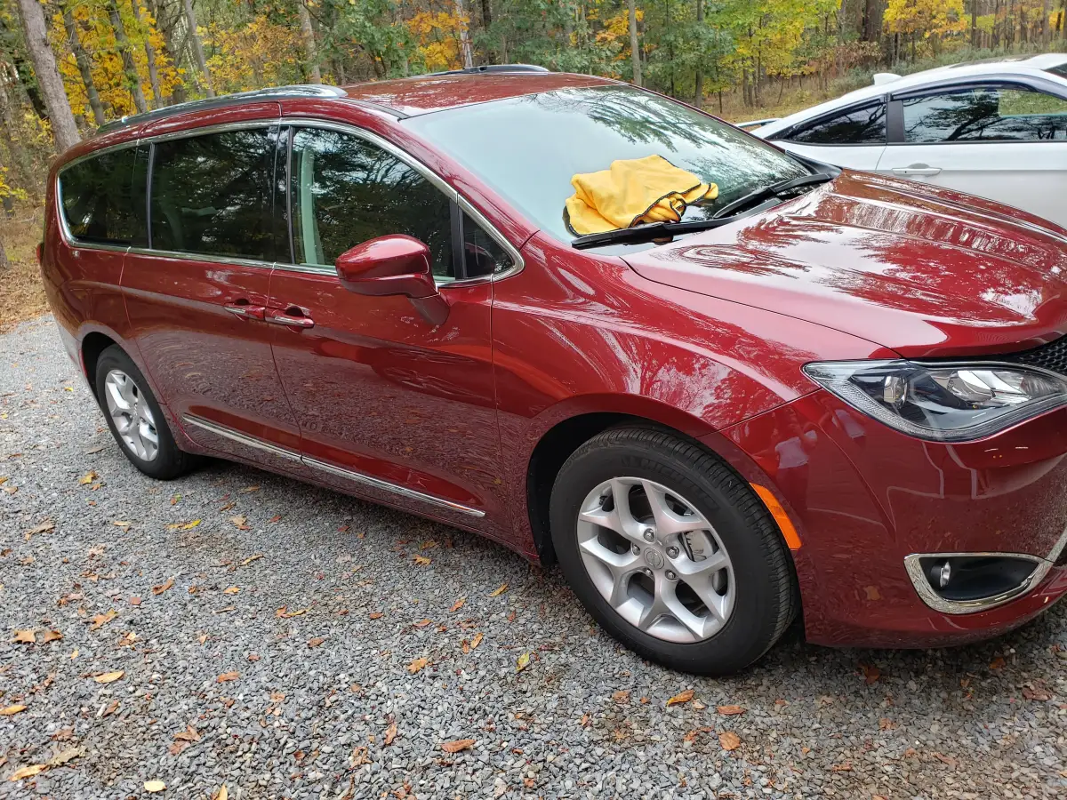 Dark red Chrysler Pacifica minivan with glossy finish parked in a garage driveway