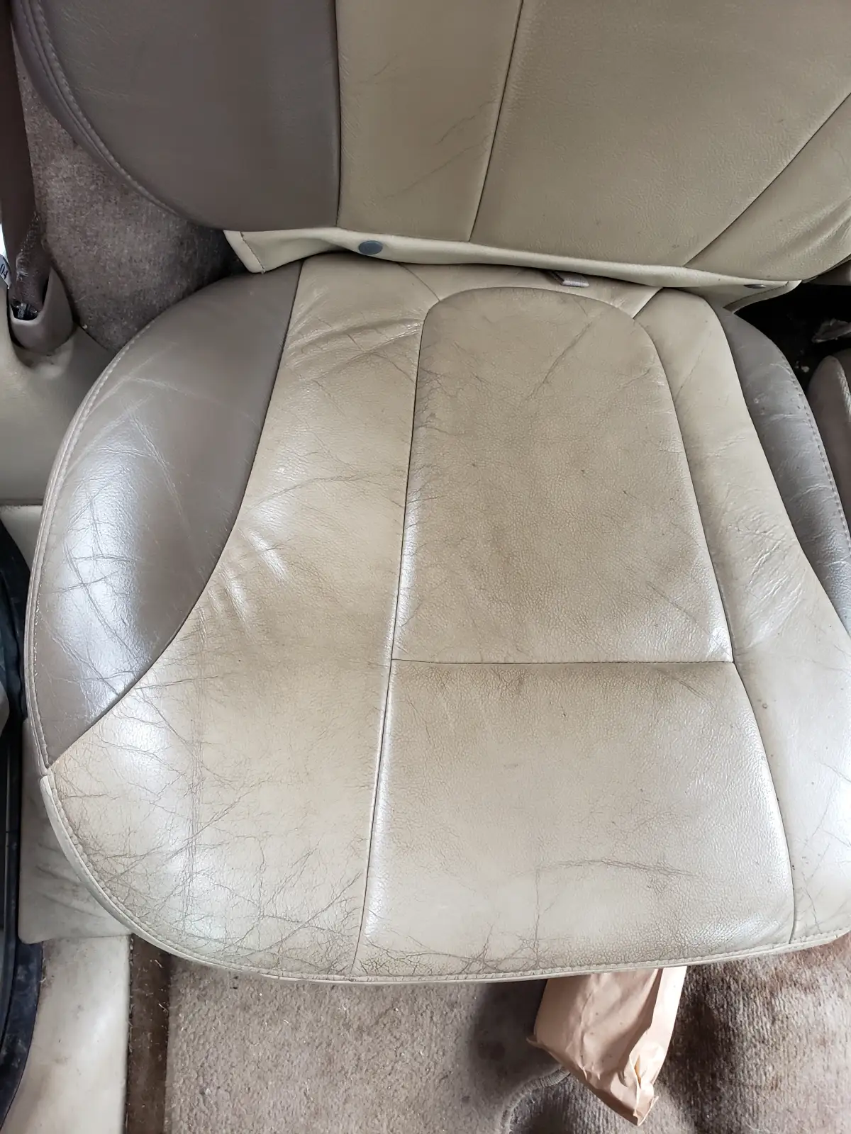 Aged tan leather seat showing wear and cracks in a car interior needing detail