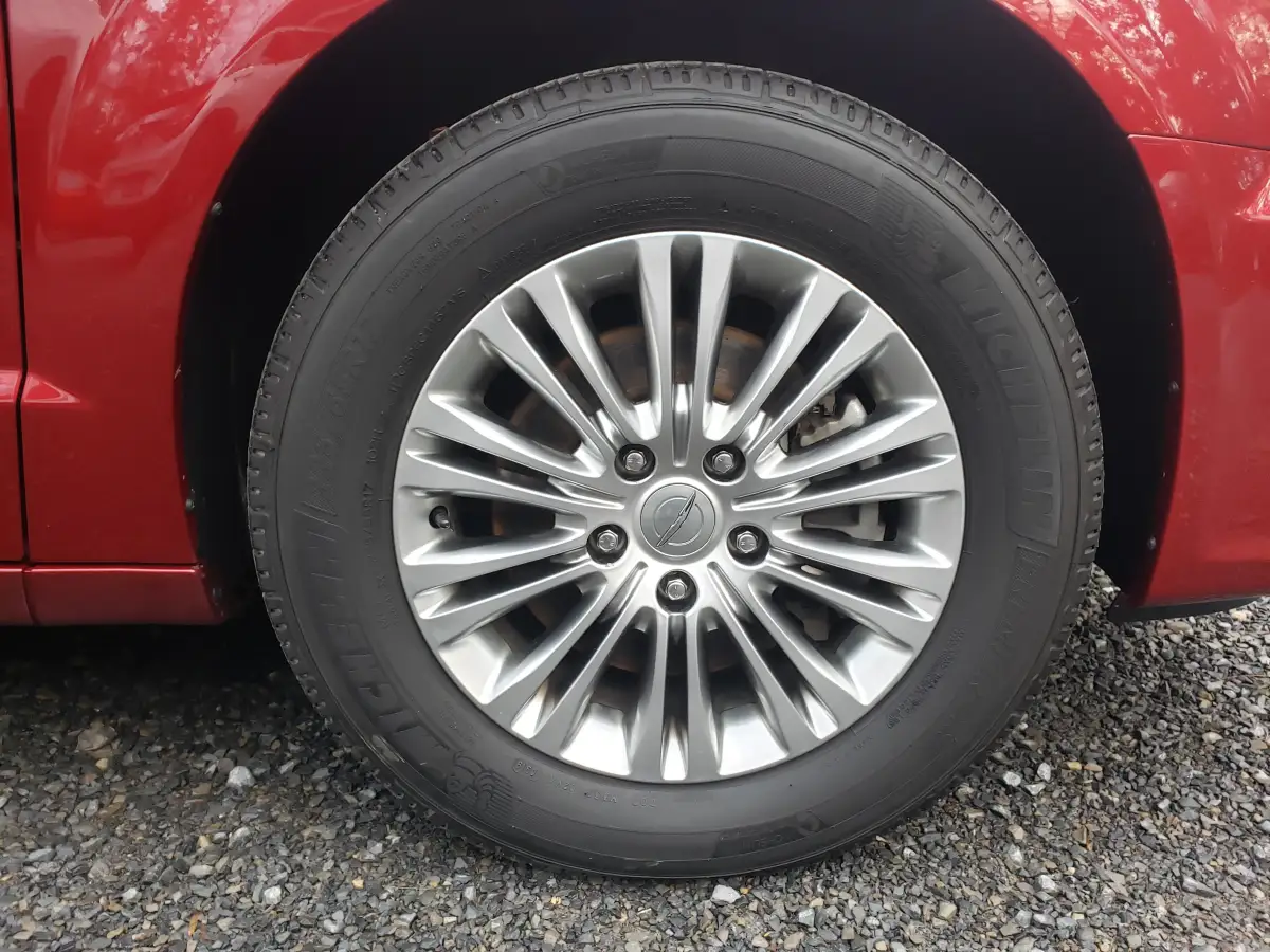 Close-up of a polished chrome wheel and tire on a red minivan after detailing