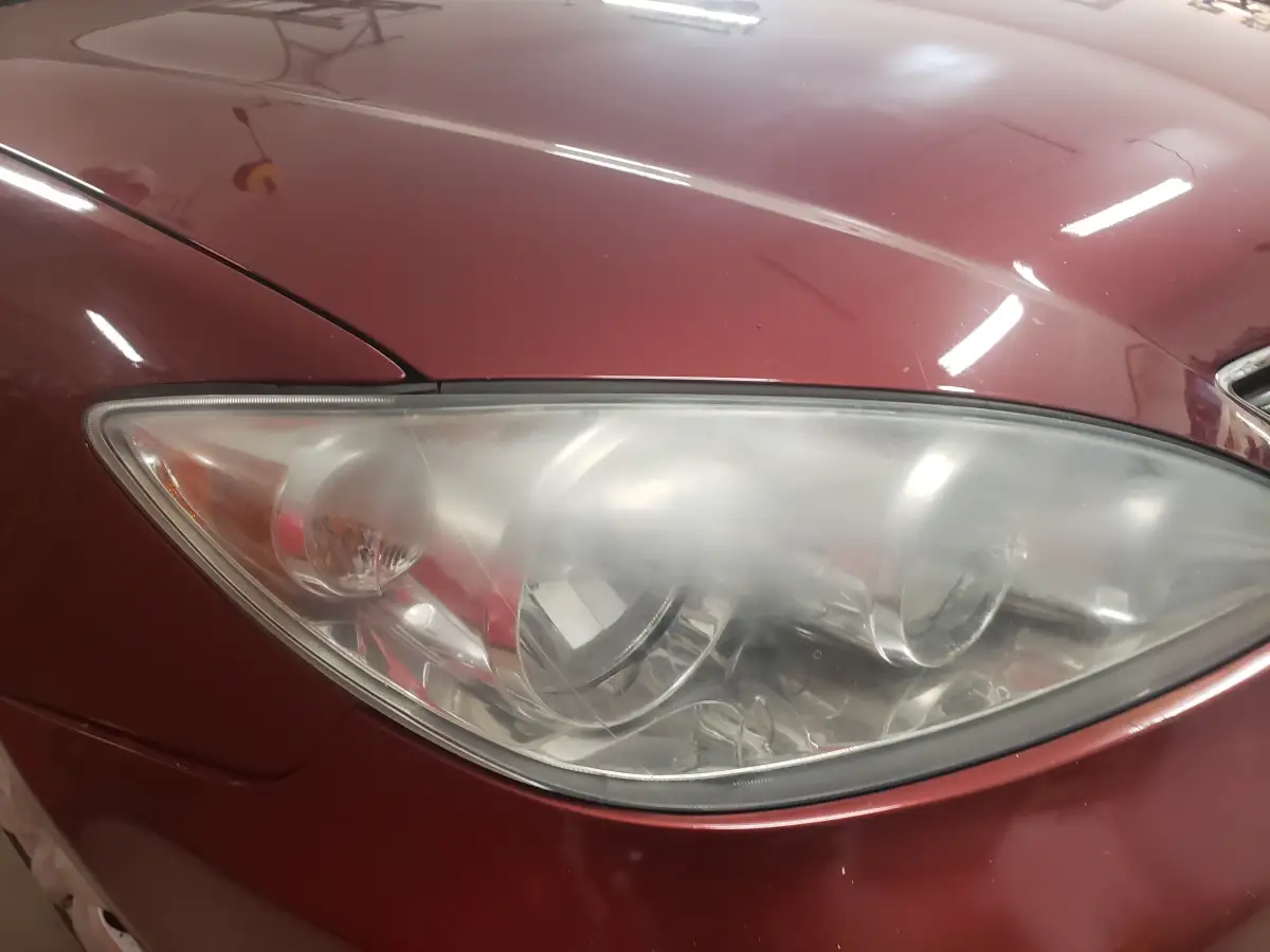 Restored foggy headlight lens on a maroon sedan mid-headlight restoration
