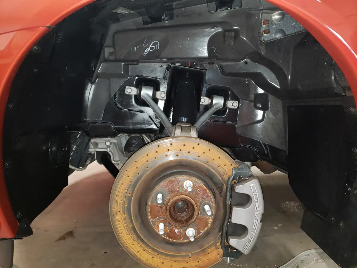 Close-up of a Corvette brake rotor and caliper in the wheel well after cleaning