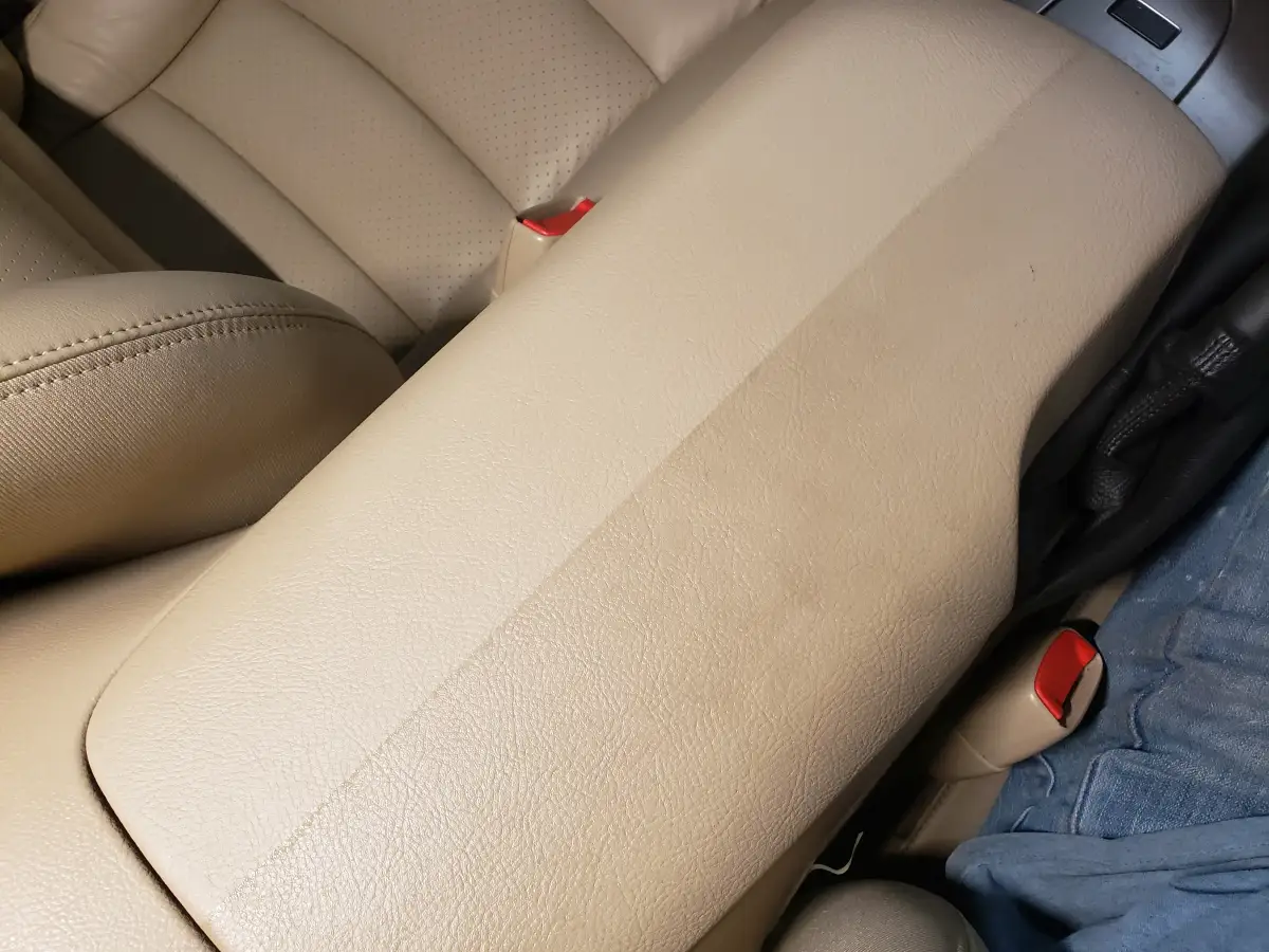 Half-cleaned tan leather center console showing a before-and-after conditioning line