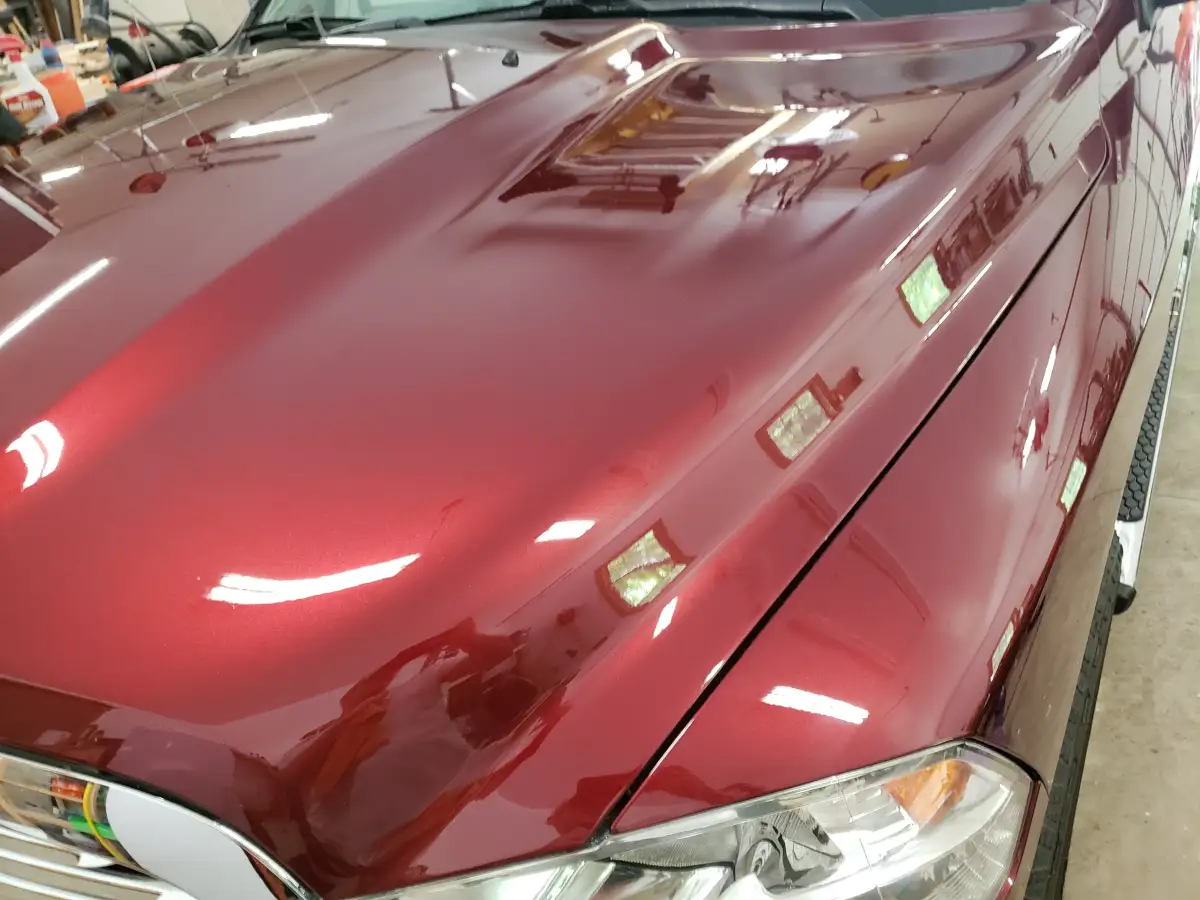 Maroon minivan hood with painter's tape marking swirl marks for paint correction