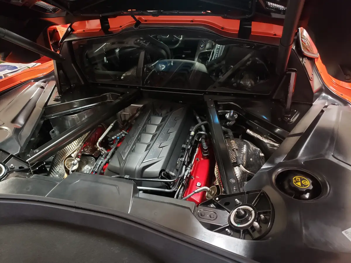 Detailed engine bay of an orange Corvette with open hood and clean components