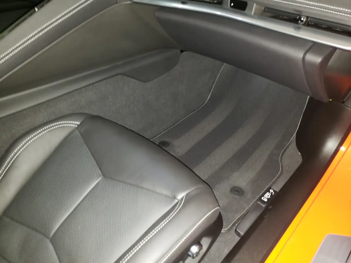 Clean black leather rear footwell and seat back of an orange sports car interior
