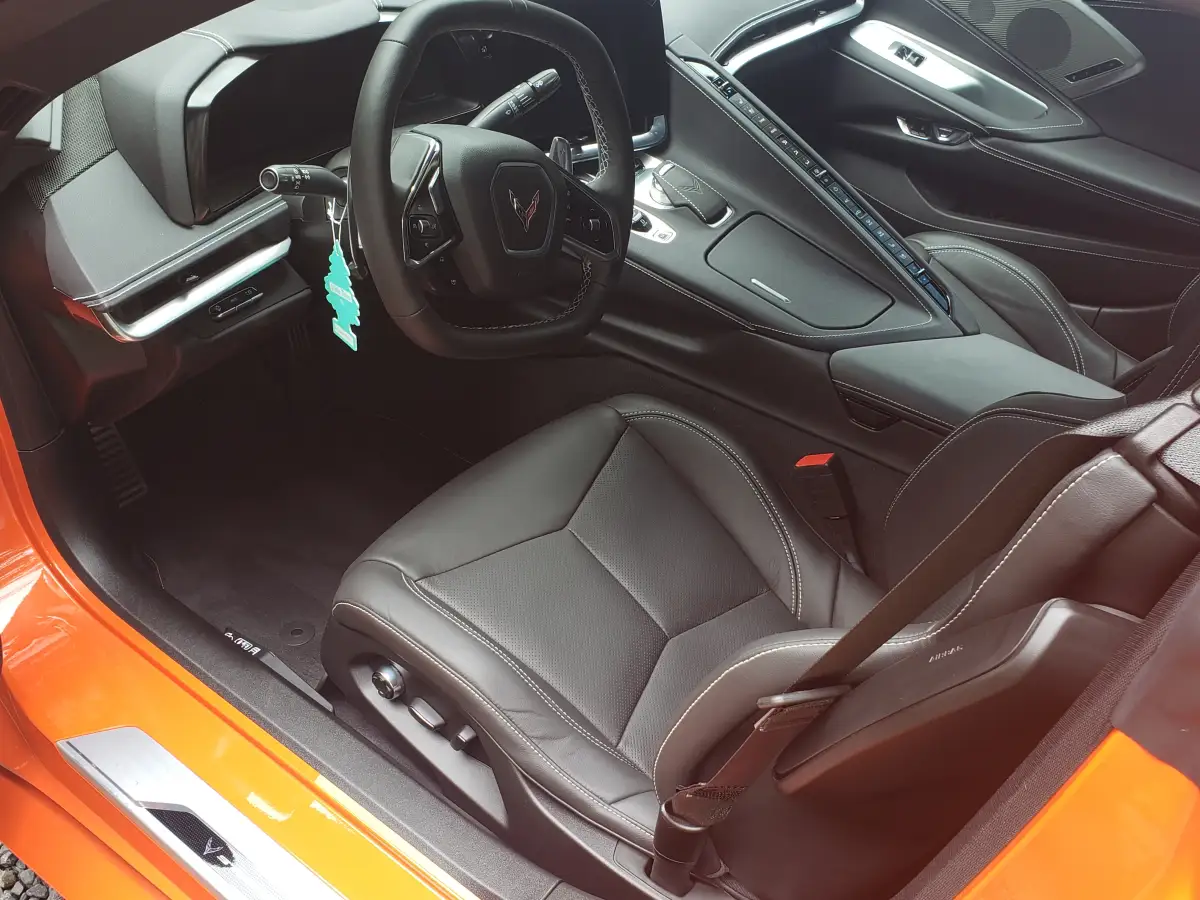 Clean black leather dashboard and seats inside an orange Corvette Stingray