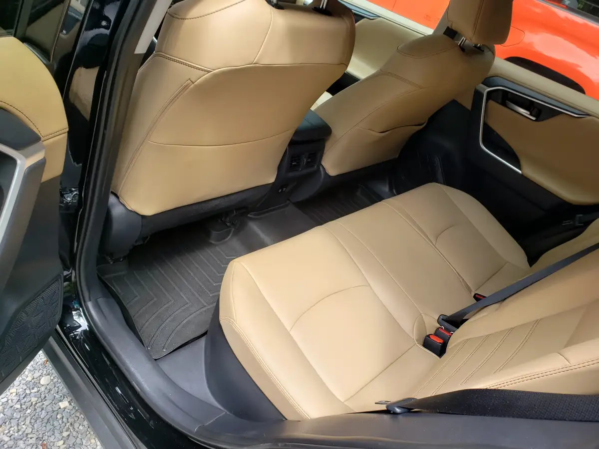 Clean tan leather rear seats and floor mats inside a black Toyota RAV4