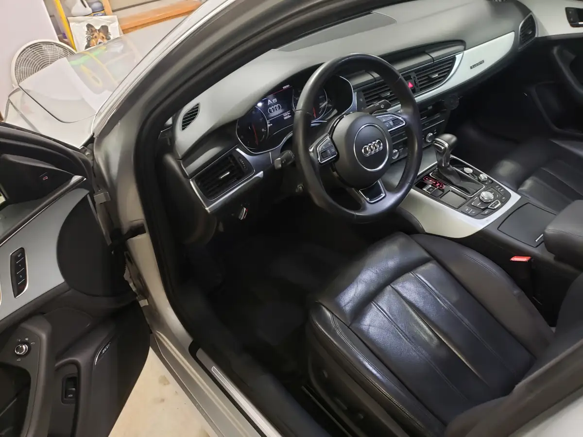 Clean black leather dashboard and steering wheel inside a silver Audi A6