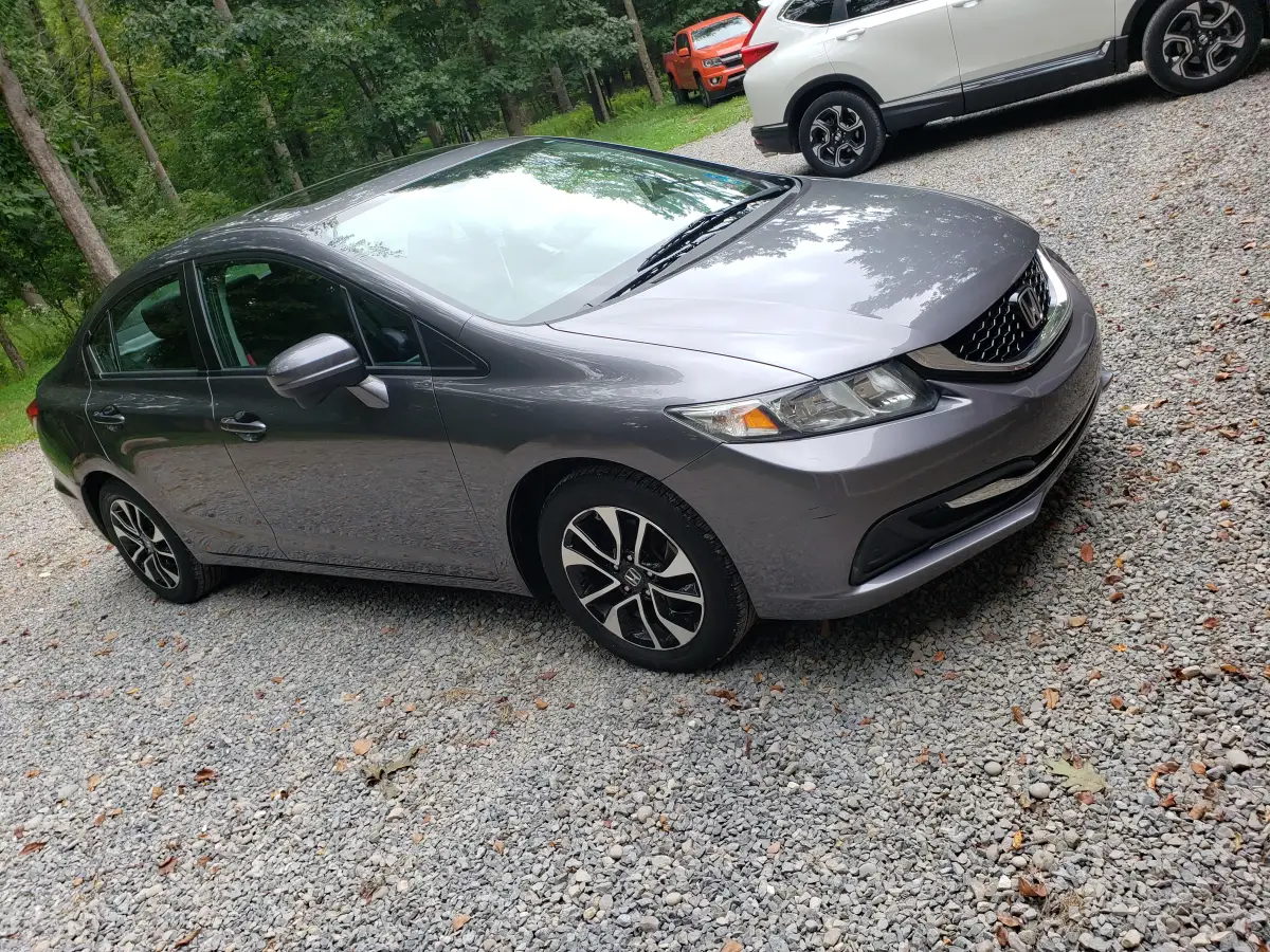 Detailed gray Honda Civic sedan parked on a gravel driveway among trees