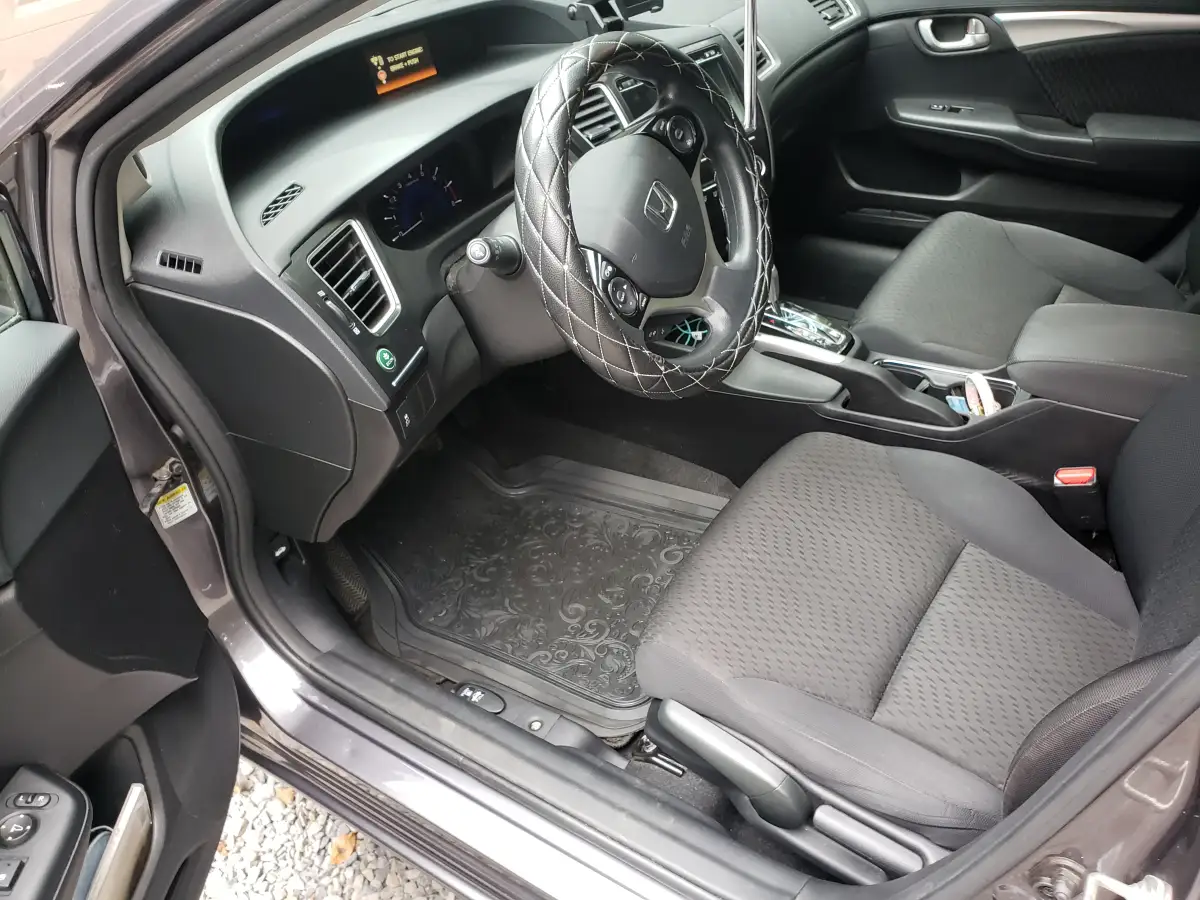 Detailed gray cloth seats and dashboard of a dark Honda Civic interior with steering wheel cover
