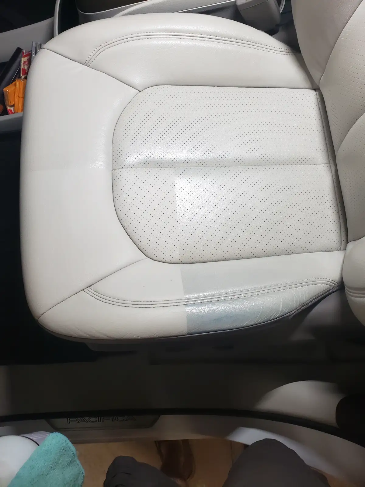 Close-up of a cleaned cream leather car seat cushion showing a two-tone cleaning contrast