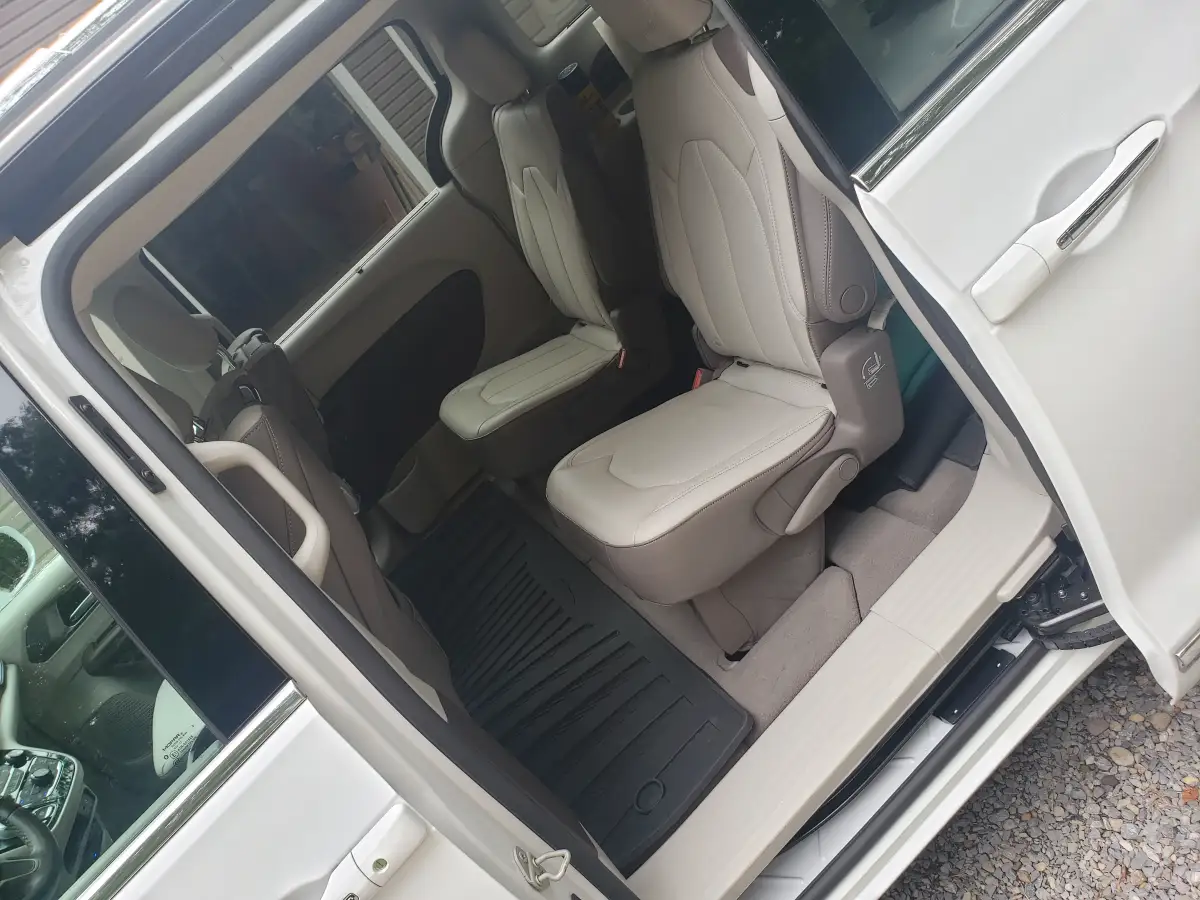 Clean tan leather third-row minivan seats and cargo area viewed through open side door