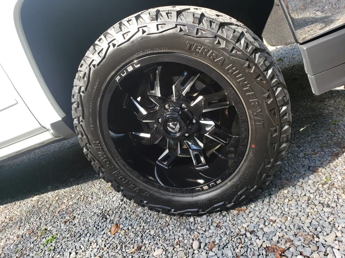 Close-up of a black off-road wheel and all-terrain tire on a detailed truck