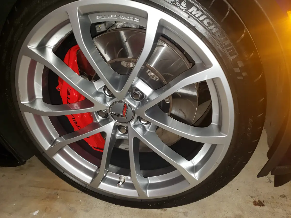 Close-up of a Corvette chrome wheel with red brake caliper and Michelin tire after cleaning
