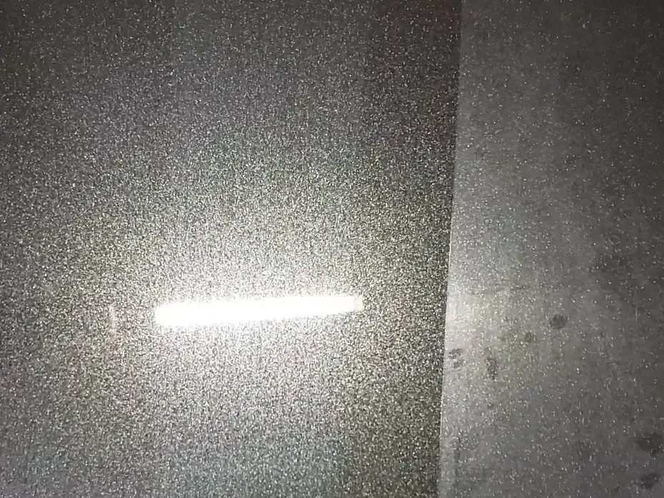 Black Chrysler Pacifica panel under a work light, half swirled and hazy, half polished to a mirror, with a sharp line between them