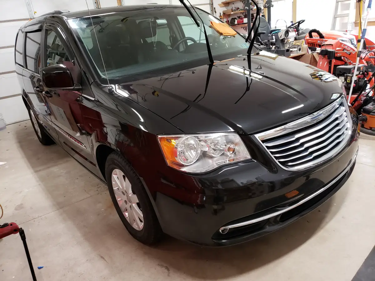 Dark gray Chrysler minivan with glossy finish parked in a garage after detailing