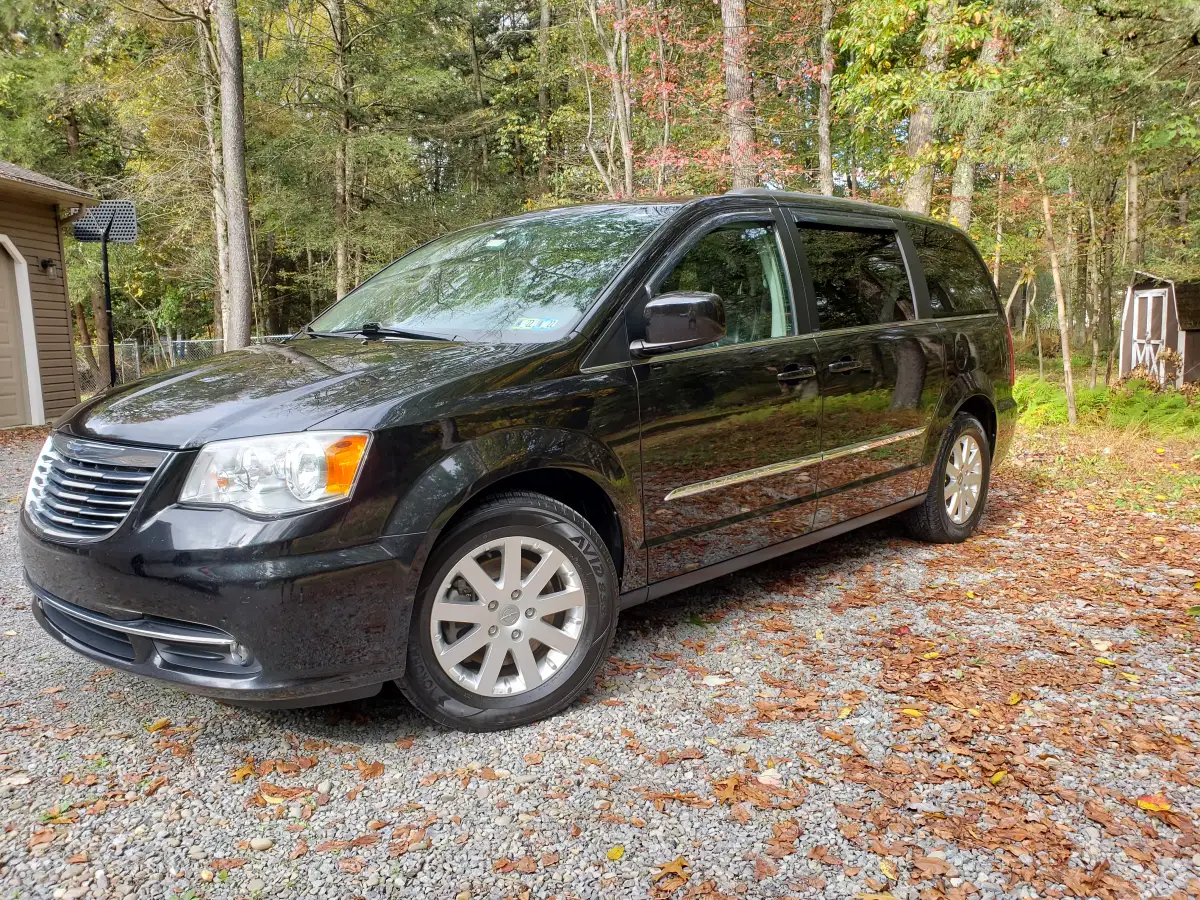 Freshly detailed black Chrysler Town and Country minivan parked among fall foliage