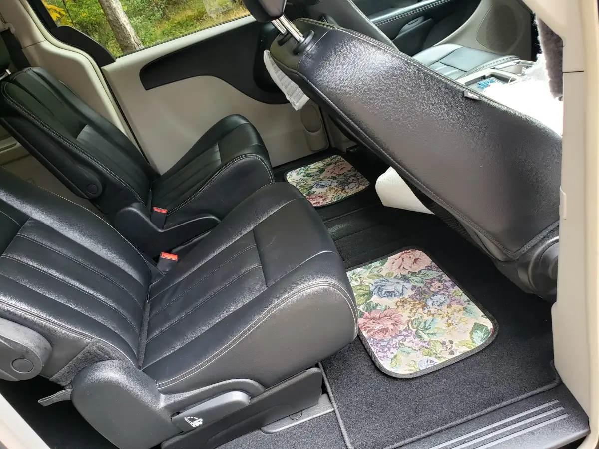 Clean black leather second-row minivan seats with floral-print floor mats after interior detailing